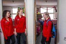 Female students smiling in front of their dorm rooms